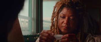 Movie still from “End of the Road” (2022), directed by Millicent Shelton – A woman with dreads is holding a cup of tea; Close Up shot, Low angle