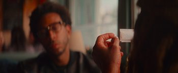 Movie still from “End of the Road” (2022), directed by Millicent Shelton – A man holding a piece of paper in front of a window; Extreme Close Up shot, High angle