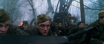 Movie still from “Enemy at the Gates” (2001), directed by Jean-Jacques Annaud – A group of men sitting on top of a boat in the water; Medium shot, Low angle