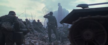 Movie still from “Enemy at the Gates” (2001), directed by Jean-Jacques Annaud – A soldier saluting while standing in the ruins of a building; Wide shot, Low angle