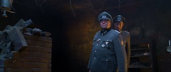 Movie still from “Enemy at the Gates” (2001), directed by Jean-Jacques Annaud – A man in a military uniform standing next to another man; Medium shot, Low angle
