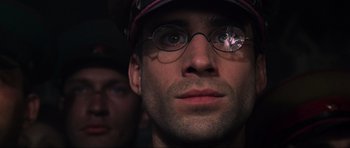 Movie still from “Enemy at the Gates” (2001), directed by Jean-Jacques Annaud – A person wearing glasses and a hat; Close Up shot, Low angle