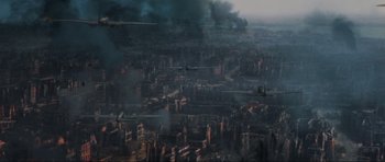 Movie still from “Enemy at the Gates” (2001), directed by Jean-Jacques Annaud – An aerial view of a city with smoke billowing from it; Extreme Wide shot, High angle