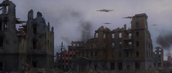 Movie still from “Enemy at the Gates” (2001), directed by Jean-Jacques Annaud – An image of an airplane flying in the sky over a city; Extreme Wide shot, Low angle