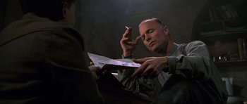 Movie still from “Enemy at the Gates” (2001), directed by Jean-Jacques Annaud – A man sitting in front of another man smoking a cigarette; Close Up shot, Low angle