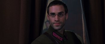 Movie still from “Enemy at the Gates” (2001), directed by Jean-Jacques Annaud – A person wearing glasses and a uniform; Close Up shot, Over the shoulder angle