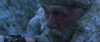 Movie still from “Enemy at the Gates” (2001), directed by Jean-Jacques Annaud – An old man with a beard and a hat is covered in snow; Close Up shot, Overhead angle