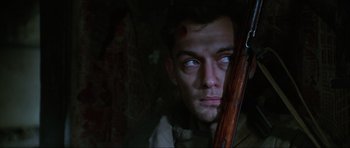 Movie still from “Enemy at the Gates” (2001), directed by Jean-Jacques Annaud – A man holding a rifle in a dark room; Close Up shot, Low angle