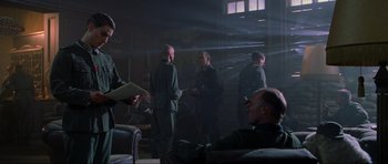 Movie still from “Enemy at the Gates” (2001), directed by Jean-Jacques Annaud – A group of men standing around in a room; Wide shot, Over the shoulder angle