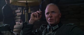 Movie still from “Enemy at the Gates” (2001), directed by Jean-Jacques Annaud – An older man holding a cigarette in his right hand; Close Up shot, Low angle