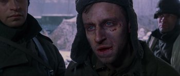 Movie still from “Enemy at the Gates” (2001), directed by Jean-Jacques Annaud – A person wearing a hat with blood all over his face; Close Up shot, Over the shoulder angle
