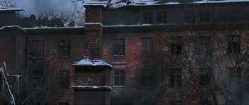 Movie still from “Enemy at the Gates” (2001), directed by Jean-Jacques Annaud – An old brick building with a snowy roof and windows; Extreme Wide shot, Low angle