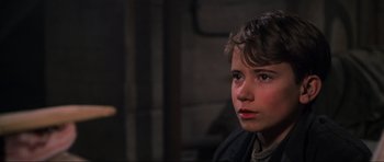 Movie still from “Enemy at the Gates” (2001), directed by Jean-Jacques Annaud – A young boy is sitting in front of a brick wall; Close Up shot, Over the shoulder angle