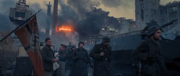 Movie still from “Enemy at the Gates” (2001), directed by Jean-Jacques Annaud – A group of men walking in front of an industrial area; Wide shot, Low angle