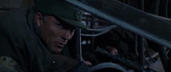 Movie still from “Enemy at the Gates” (2001), directed by Jean-Jacques Annaud – A man with a gun in his hand and wearing a hat; Close Up shot, Low angle