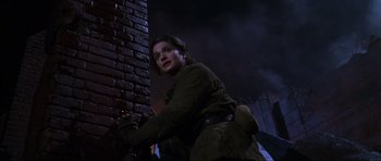 Movie still from “Enemy at the Gates” (2001), directed by Jean-Jacques Annaud – A woman leaning against a brick wall at night; Medium shot, Low angle