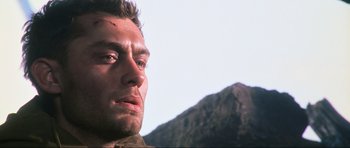 Movie still from “Enemy at the Gates” (2001), directed by Jean-Jacques Annaud – A man's face in front of a mountain; Close Up shot, Low angle