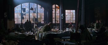 Movie still from “Enemy at the Gates” (2001), directed by Jean-Jacques Annaud – A group of people sitting on a bed in a room; Wide shot, High angle