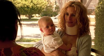 Movie still from “Erin Brockovich” (2000), directed by Steven Soderbergh – A woman holding a baby wearing a neck brace; Close Up shot, Low angle