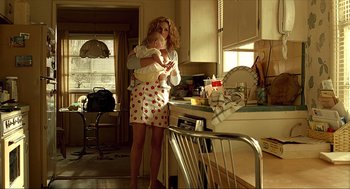 Movie still from “Erin Brockovich” (2000), directed by Steven Soderbergh – A woman holding a baby in her arms in a kitchen; Medium shot, Low angle
