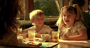 Movie still from “Erin Brockovich” (2000), directed by Steven Soderbergh – Two children are sitting at a table with drinks; Medium shot, Over the shoulder angle