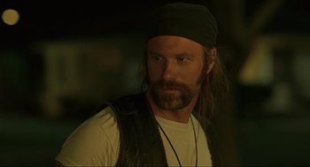 Movie still from “Erin Brockovich” (2000), directed by Steven Soderbergh – A man with long hair and a beard wearing a black hat; Close Up shot, Over the shoulder angle