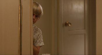 Movie still from “Erin Brockovich” (2000), directed by Steven Soderbergh – A young boy leaning against a wall in a room; Medium shot, Over the shoulder angle