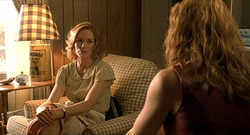 Movie still from “Erin Brockovich” (2000), directed by Steven Soderbergh – A woman sitting on top of a couch next to another woman; Medium shot, Over the shoulder angle