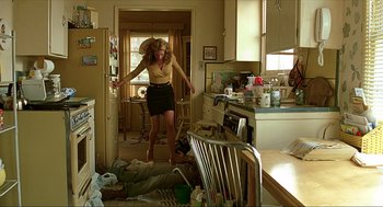 Movie still from “Erin Brockovich” (2000), directed by Steven Soderbergh – A woman is jumping in the air in a messy kitchen; Wide shot, Low angle