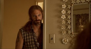 Movie still from “Erin Brockovich” (2000), directed by Steven Soderbergh – A man with long hair and a beard standing in front of a door; Close Up shot, Over the shoulder angle