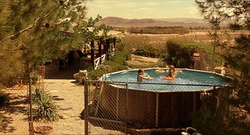 Movie still from “Erin Brockovich” (2000), directed by Steven Soderbergh – Two people in an above - ground swimming pool in a backyard; Extreme Wide shot, High angle