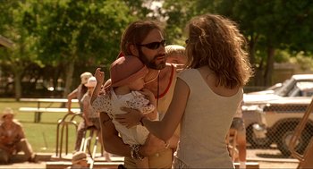 Movie still from “Erin Brockovich” (2000), directed by Steven Soderbergh – A man holding a baby in his arms while a woman looks on; Medium shot, Over the shoulder angle