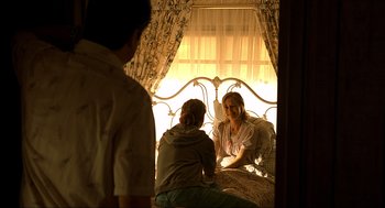 Movie still from “Erin Brockovich” (2000), directed by Steven Soderbergh – A woman sitting on top of a bed next to two boys; Medium shot, Over the shoulder angle