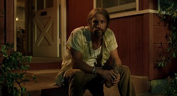 Movie still from “Erin Brockovich” (2000), directed by Steven Soderbergh – A man sitting on the ground holding a camera; Medium shot, Low angle