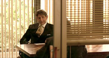 Movie still from “Erin Brockovich” (2000), directed by Steven Soderbergh – A man sitting at a table in front of a window; Medium shot, Over the shoulder angle