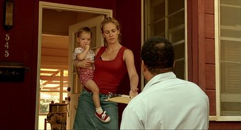 Movie still from “Erin Brockovich” (2000), directed by Steven Soderbergh – A woman holding a child while a man holds a board; Medium shot, Low angle