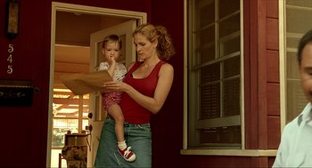 Movie still from “Erin Brockovich” (2000), directed by Steven Soderbergh – A woman holding a baby while looking at a piece of paper; Medium shot, Low angle