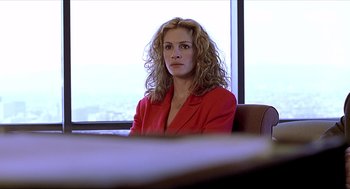 Movie still from “Erin Brockovich” (2000), directed by Steven Soderbergh – A woman sitting in a chair in front of a large window; Close Up shot, Over the shoulder angle