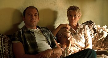 Movie still from “Erin Brockovich” (2000), directed by Steven Soderbergh – A man , woman , and a child sitting on a couch; Medium shot, Low angle