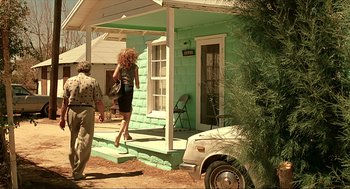 Movie still from “Erin Brockovich” (2000), directed by Steven Soderbergh – A woman in a black dress walking down the steps of a house; Wide shot, Low angle