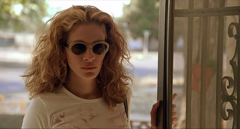 Movie still from “Erin Brockovich” (2000), directed by Steven Soderbergh – A woman with curly red hair wearing sunglasses; Close Up shot, Low angle