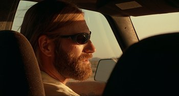 Movie still from “Erin Brockovich” (2000), directed by Steven Soderbergh – A man with a beard and sunglasses driving a car; Close Up shot, Low angle