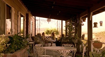 Movie still from “Erin Brockovich” (2000), directed by Steven Soderbergh – Two women sitting on a porch with tables and chairs; Wide shot, Low angle