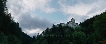Movie still from “A Hidden Life” (2019), directed by Terrence Malick – A castle on top of a hill with trees in the foreground; Extreme Wide shot, High angle
