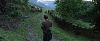 Movie still from “A Hidden Life” (2019), directed by Terrence Malick – A woman is walking down a dirt road; Wide shot, High angle