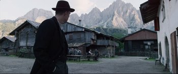 Movie still from “A Hidden Life” (2019), directed by Terrence Malick – A group of people sitting in front of a building; Wide shot, Over the shoulder angle