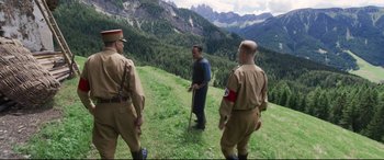 Movie still from “A Hidden Life” (2019), directed by Terrence Malick – A group of men standing on top of a grass covered hill; Wide shot, High angle