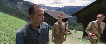 Movie still from “A Hidden Life” (2019), directed by Terrence Malick – Two men in military uniforms are standing in a field; Medium shot, Over the shoulder angle