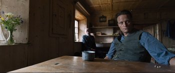 Movie still from “A Hidden Life” (2019), directed by Terrence Malick – Two men sitting at a table with a cup of coffee; Medium shot, Low angle