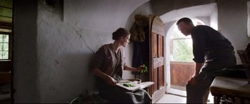 Movie still from “A Hidden Life” (2019), directed by Terrence Malick – A woman sitting on a chair holding a plate of food; Wide shot, Low angle